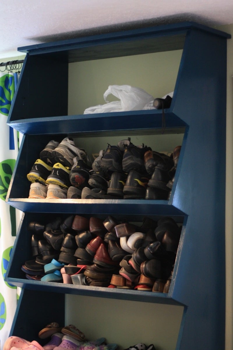 Floor to ceiling modular shoe shelves with decorative trim displaying bags  and shoes.