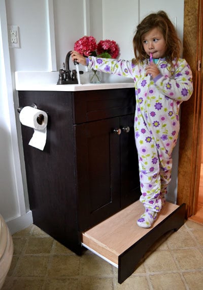 bathroom vanity with little girl standing on pullout step drawer